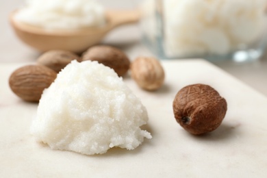 Photo of Shea butter and nuts on marble board, closeup