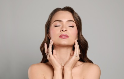 Photo of Young woman wearing elegant pearl jewelry on grey background