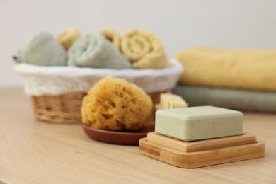 Photo of Soap bar and sponge on light wooden table, space for text. Spa therapy
