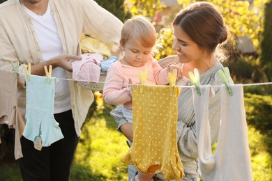Photo of Happy family near washing line with drying clothes in backyard