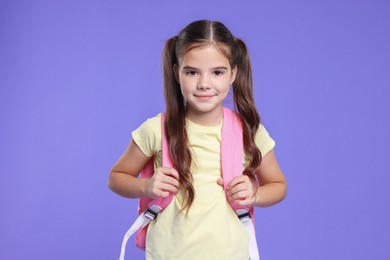 Photo of Back to school. Cute girl with backpack on violet background