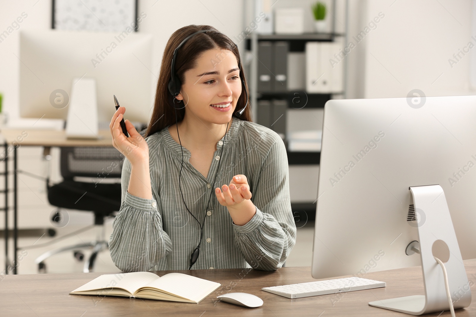 Photo of Hotline operator with headset working on computer in office