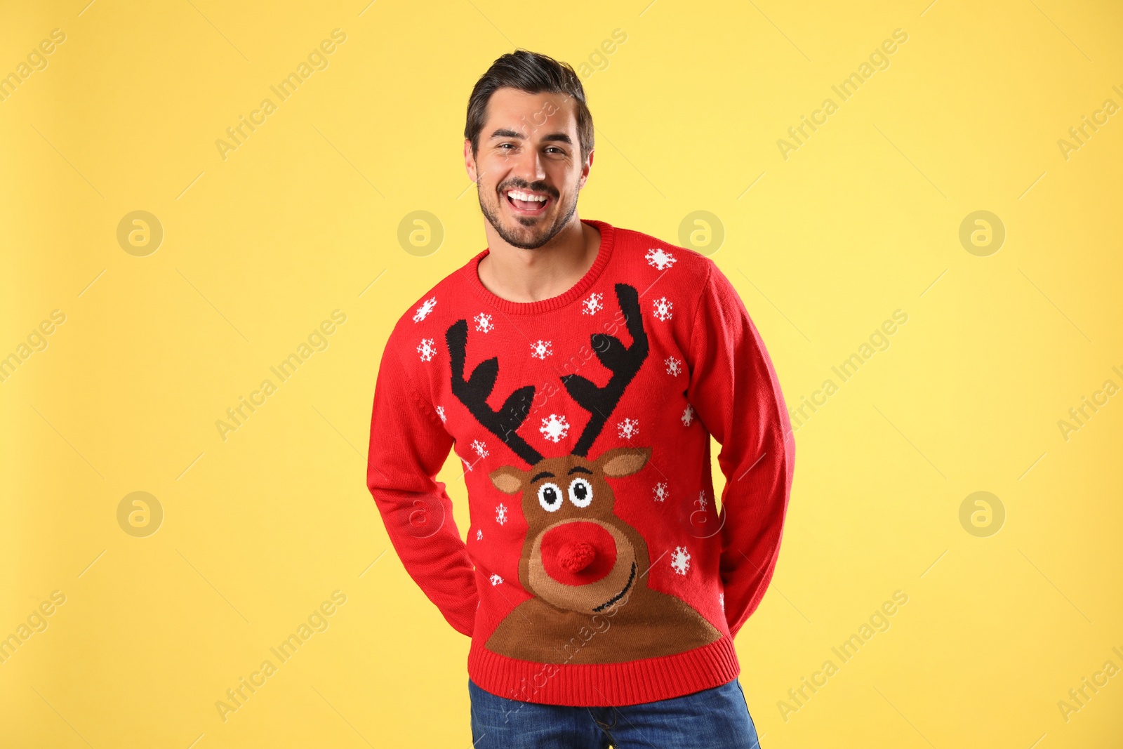 Photo of Portrait of happy young man in Christmas sweater on yellow background