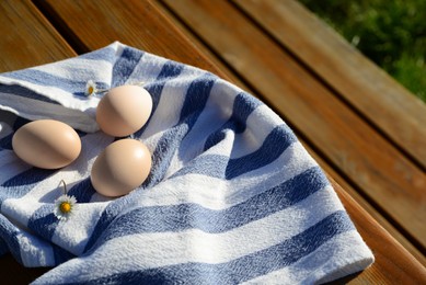 Photo of Raw duck eggs with napkin on wooden table outdoors. Space for text