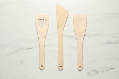 Photo of Different wooden spatulas on white marble table, flat lay