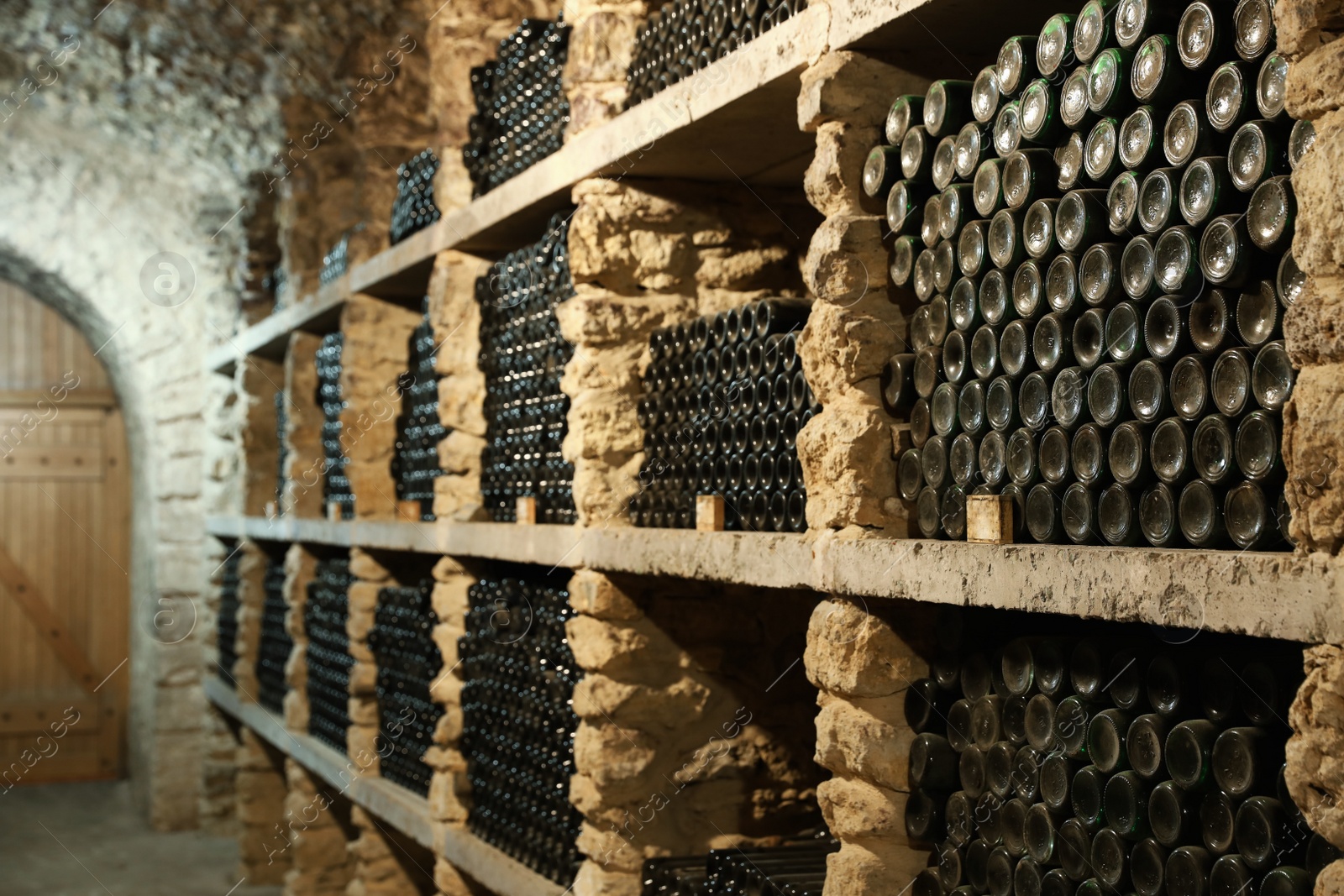 Photo of Many wine bottles on shelves in cellar