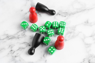 Green dices and game pieces on white marble table, above view