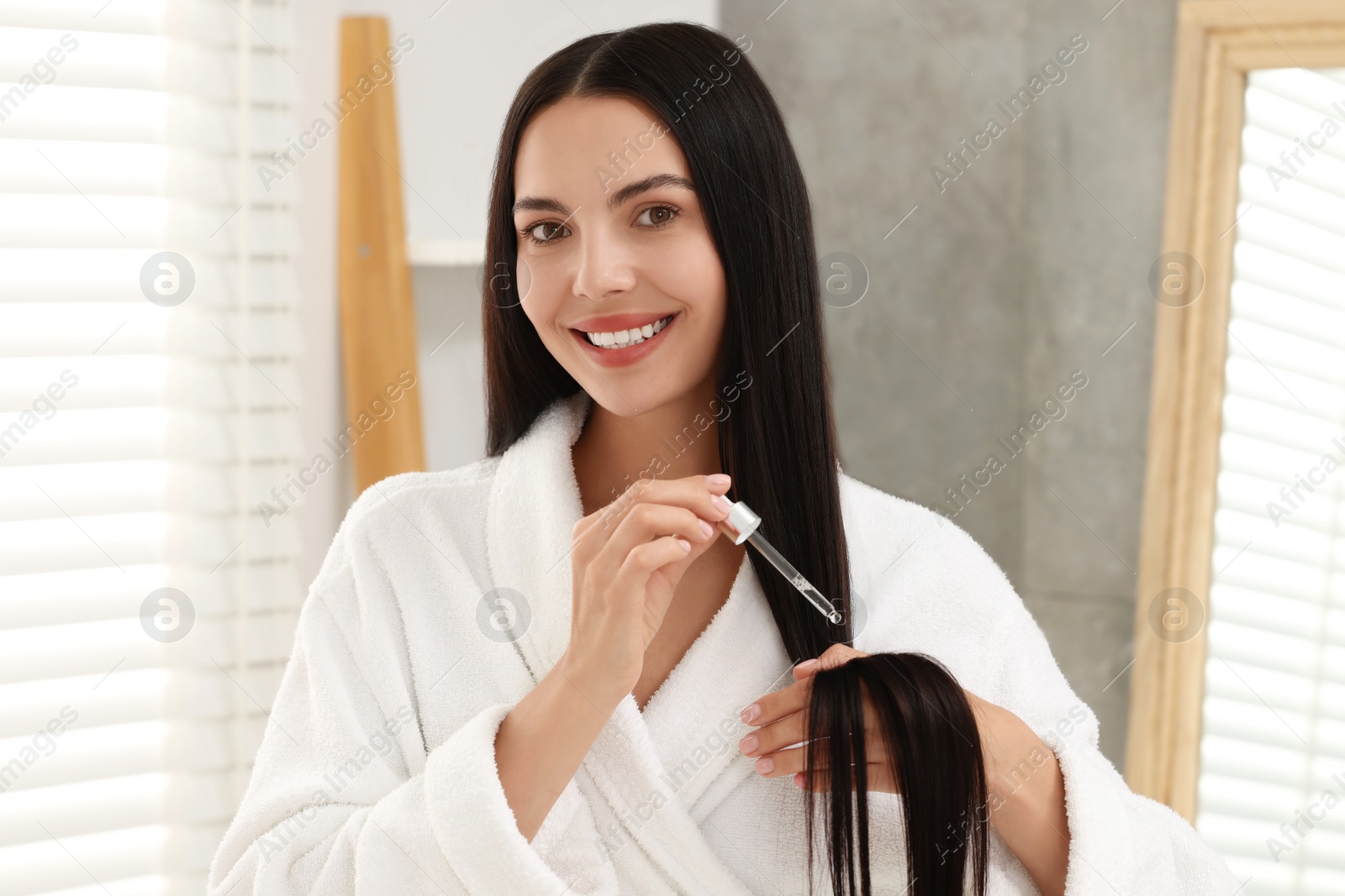 Photo of Beautiful woman applying hair serum indoors. Cosmetic product