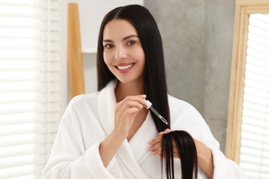 Photo of Beautiful woman applying hair serum indoors. Cosmetic product