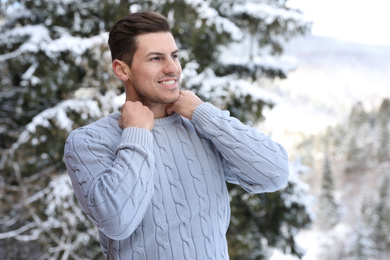 Photo of Happy man wearing warm sweater snowy fir tree