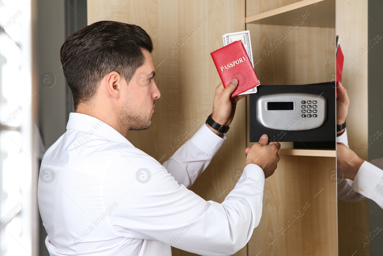 Photo of Man opening black steel safe with electronic lock at hotel