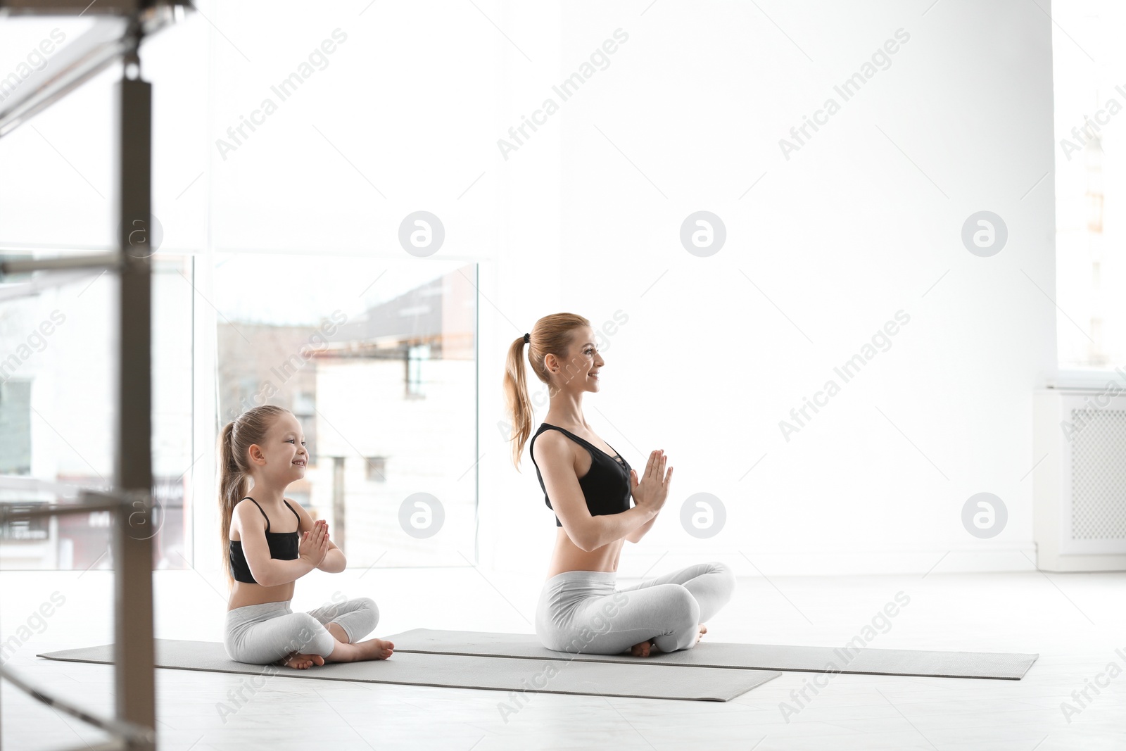 Photo of Mother and daughter in matching sportswear doing yoga together at home