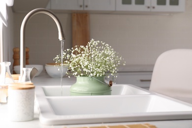 Photo of Bouquet of gypsophila flowers in sink. Kitchen interior design
