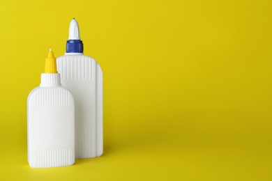 Different bottles of glue on yellow background, space for text