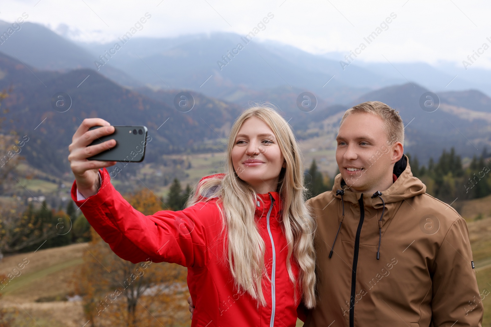 Photo of Couple taking selfie together in mountains on autumn day