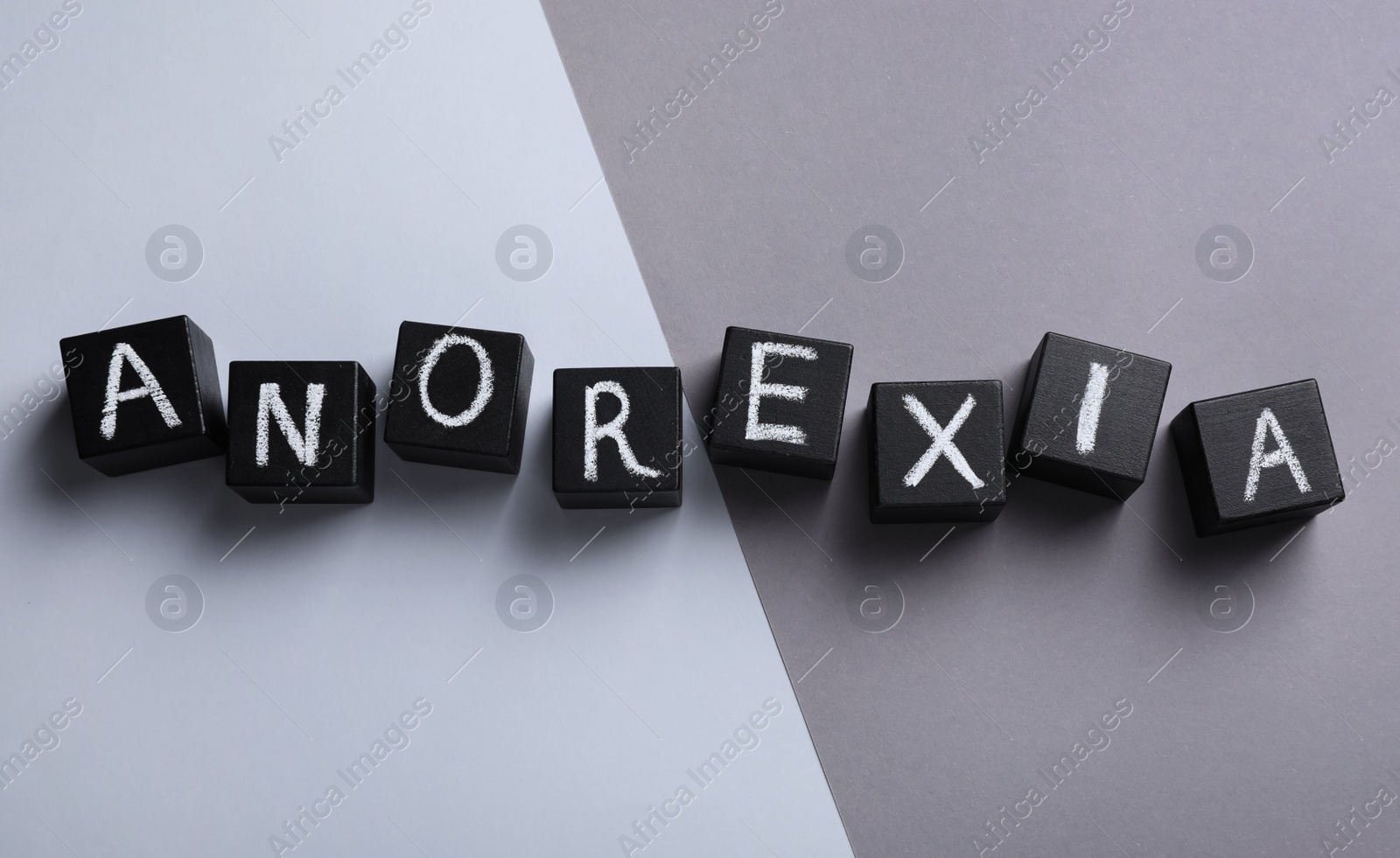 Photo of Word Anorexia made of cubes with chalked letters on color background, flat lay