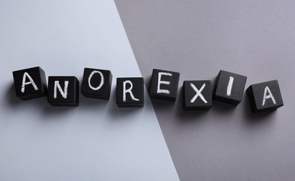 Word Anorexia made of cubes with chalked letters on color background, flat lay