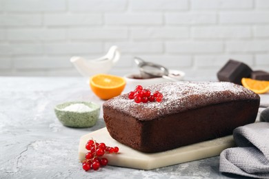 Photo of Tasty chocolate sponge cake with powdered sugar and currant on light grey textured table. Space for text