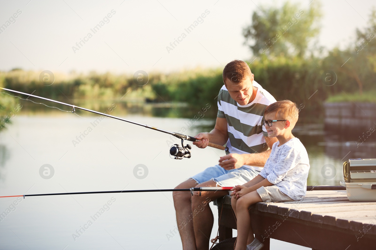 Photo of Dad and son fishing together on sunny day