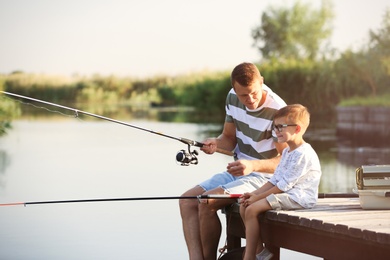 Photo of Dad and son fishing together on sunny day