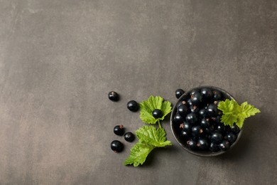 Ripe blackcurrants and leaves on grey background, flat lay. Space for text