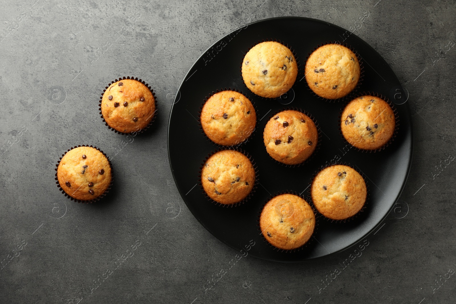 Photo of Delicious freshly baked muffins with chocolate chips on gray table, top view