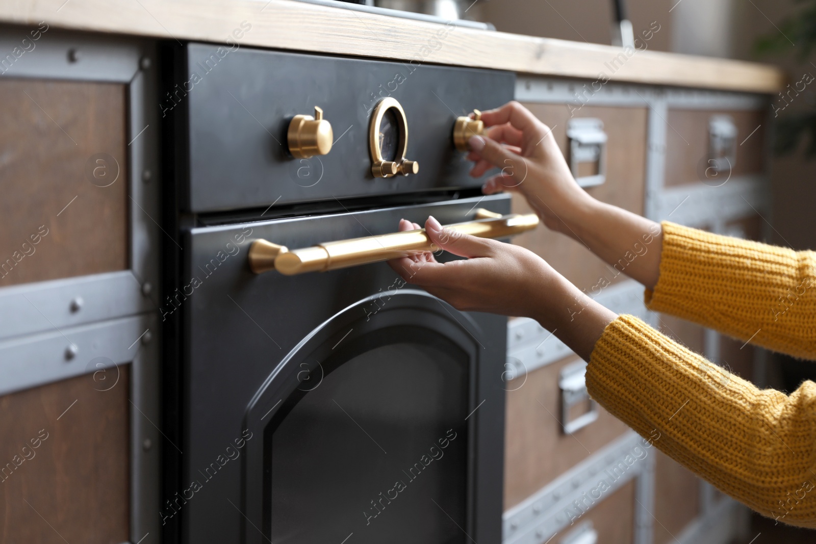 Photo of Woman using modern oven in kitchen, closeup