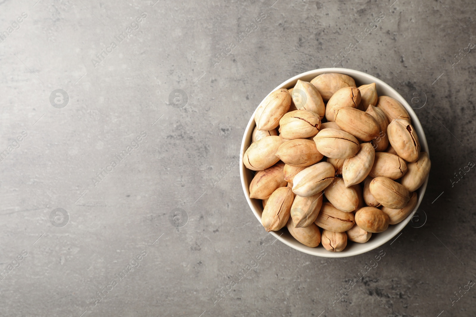 Photo of Dish with ripe pecan nuts on table, top view. Space for text