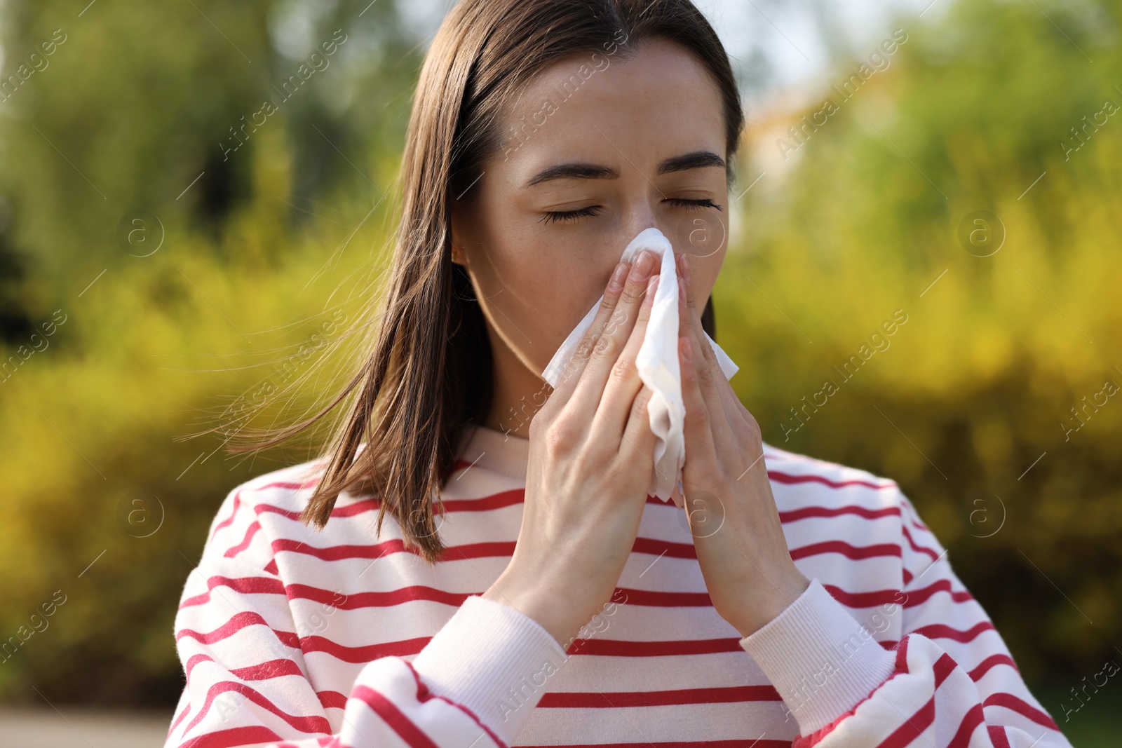 Photo of Woman with napkin suffering from seasonal allergy outdoors