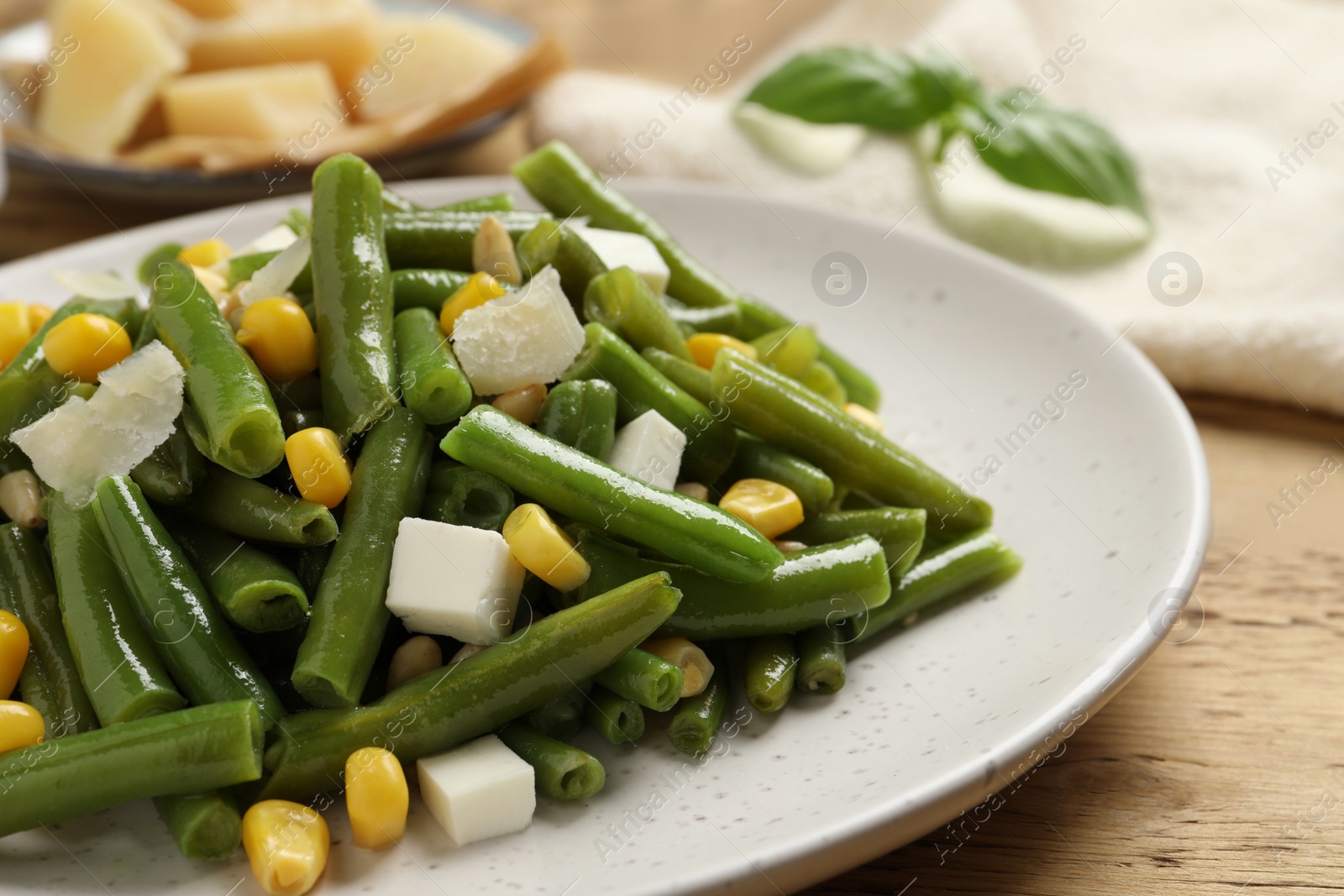 Photo of Delicious salad with green beans, corn and cheese on wooden table, closeup