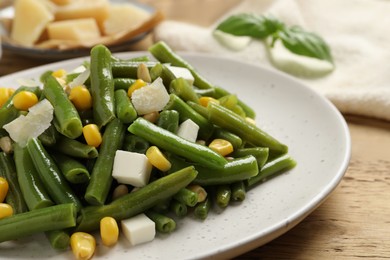Photo of Delicious salad with green beans, corn and cheese on wooden table, closeup