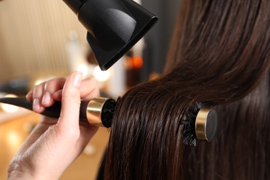 Photo of Hairdresser blow drying client's hair in salon, closeup