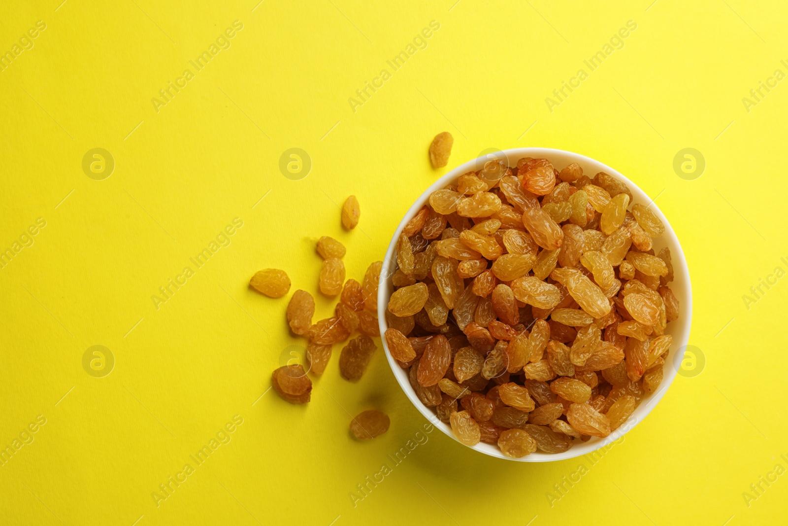 Photo of Bowl with raisins and space for text on color background, top view. Dried fruit as healthy snack