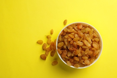 Photo of Bowl with raisins and space for text on color background, top view. Dried fruit as healthy snack