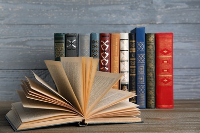 Photo of Stack of hardcover books on wooden table against grey background