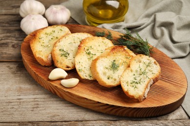 Photo of Tasty baguette with garlic, dill and oil on wooden table