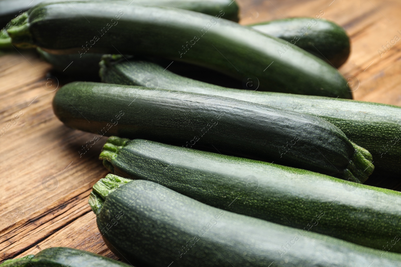 Photo of Green ripe zucchinis on wooden table, closeup