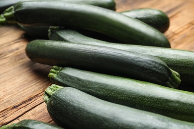 Photo of Green ripe zucchinis on wooden table, closeup