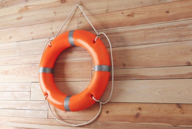 Orange lifebuoy and space for text on wooden background. Rescue equipment