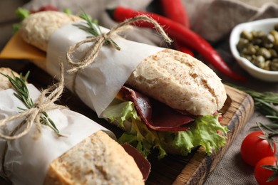 Photo of Delicious sandwiches with bresaola, cheese and lettuce on table, closeup