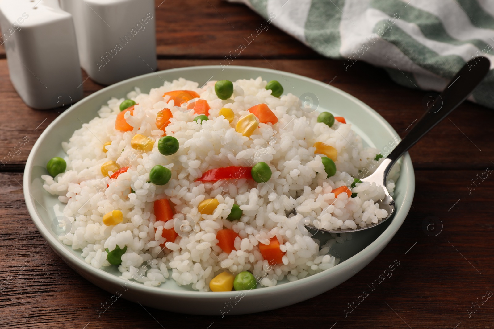 Photo of Delicious rice with vegetables served on wooden table, closeup