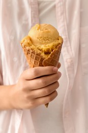 Woman holding yellow ice cream in wafer cone, closeup