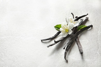 Vanilla sticks and flowers on light background