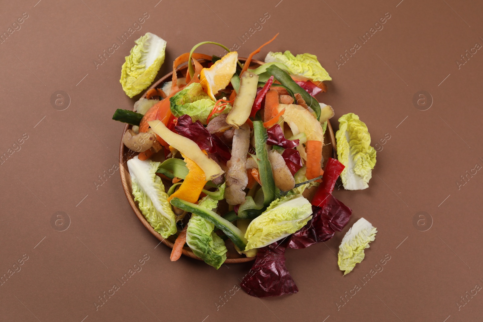 Photo of Peels of fresh vegetables on brown background, top view