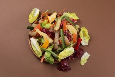 Peels of fresh vegetables on brown background, top view