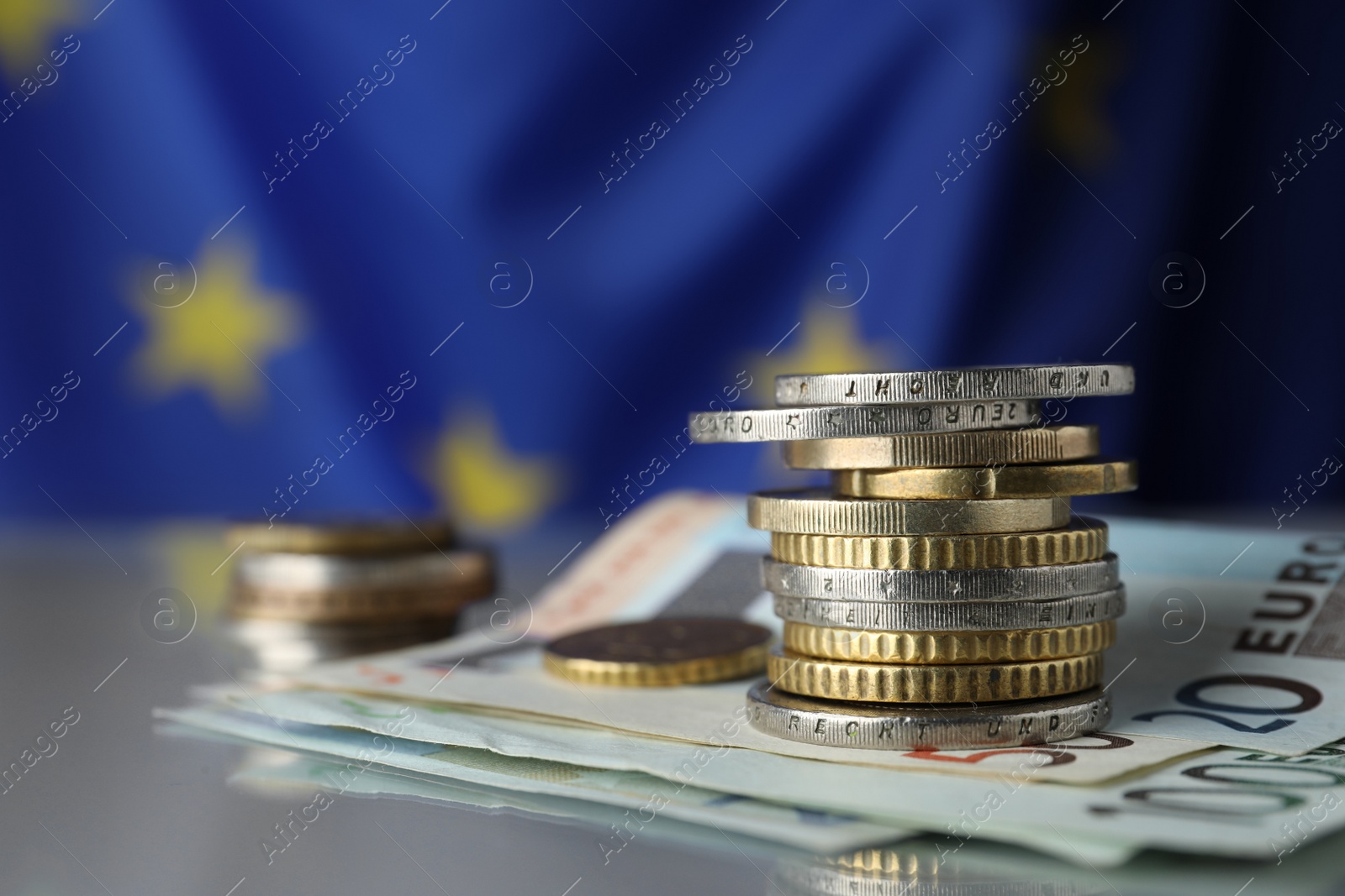 Photo of Coins and banknotes on table against European Union flag, closeup. Space for text