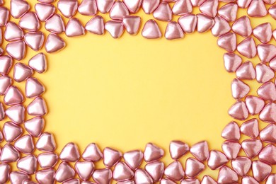 Photo of Frame made of delicious heart shaped candies on yellow background, flat lay. Space for text