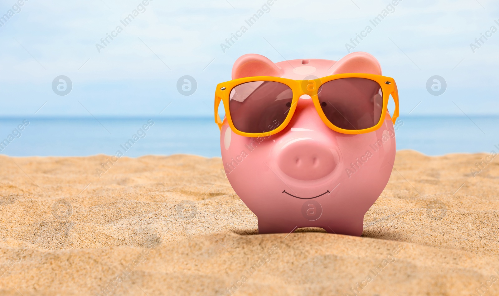 Image of Vacation savings. Piggy bank with sunglasses on sandy beach near sea. Space for text