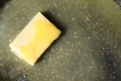 Photo of Melting butter in frying pan, top view. Space for text