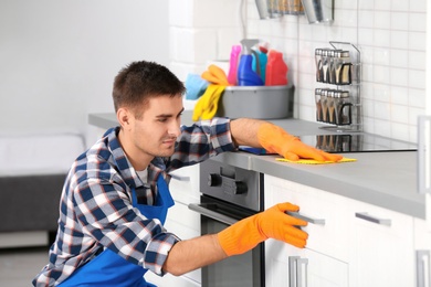 Photo of Man cleaning kitchen counter with rag in house